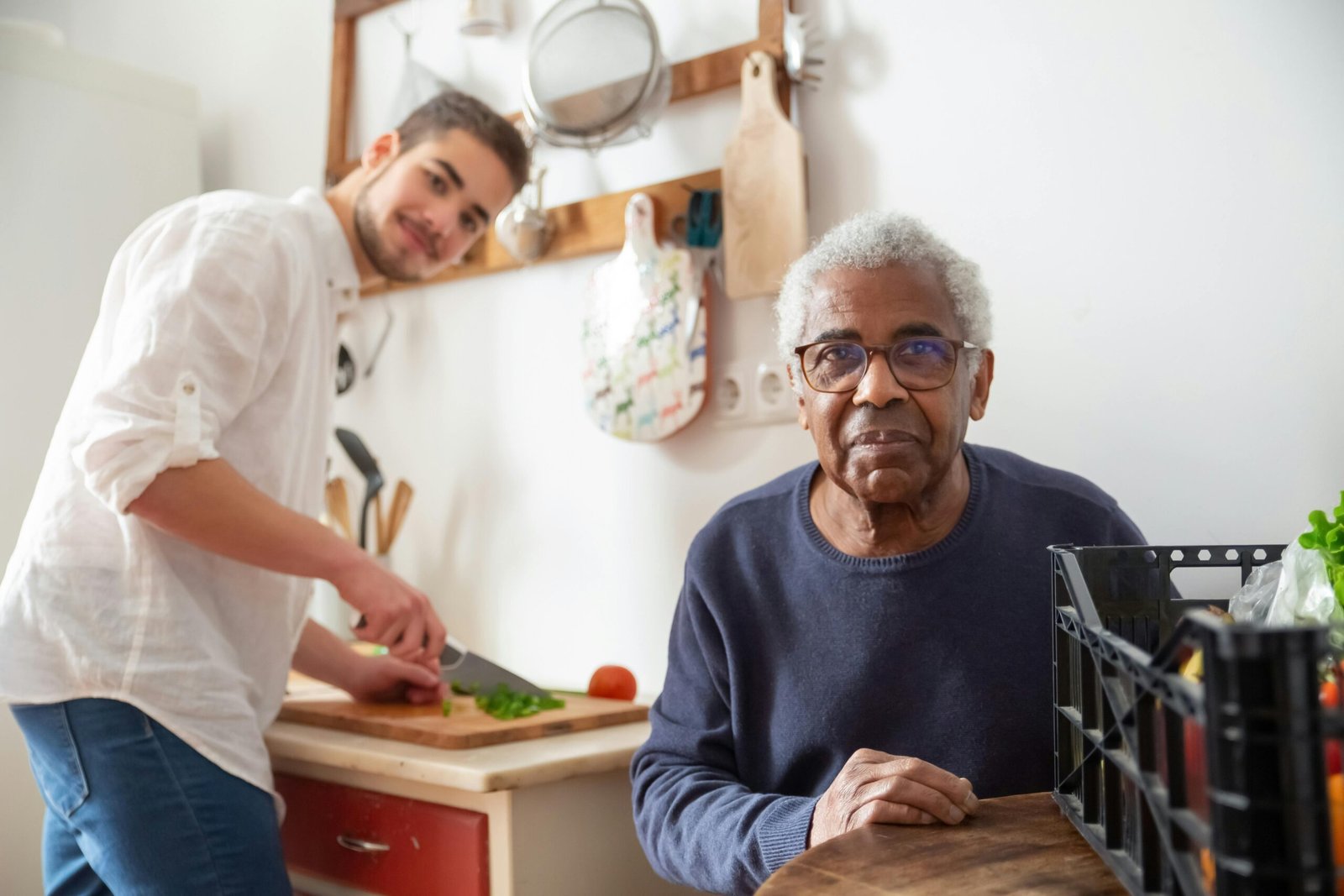 A young adult helping a senior in the kitchen, highlighting care and support at home.